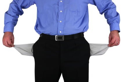 A person in a blue shirt and black pants stands with their pockets turned inside out, indicating they are empty, perhaps burdened by student loans.
