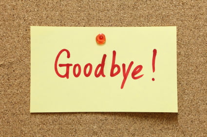 A yellow sticky note pinned to a corkboard with the word "Goodbye!" written in red, like a final message left at a bank teller's window.