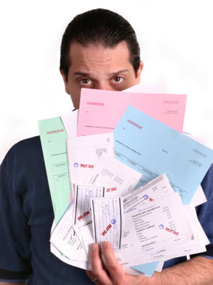 A person holding a large stack of overdue bills, representing mounting debt, in various colors partially covering their face, with a concerned expression.
