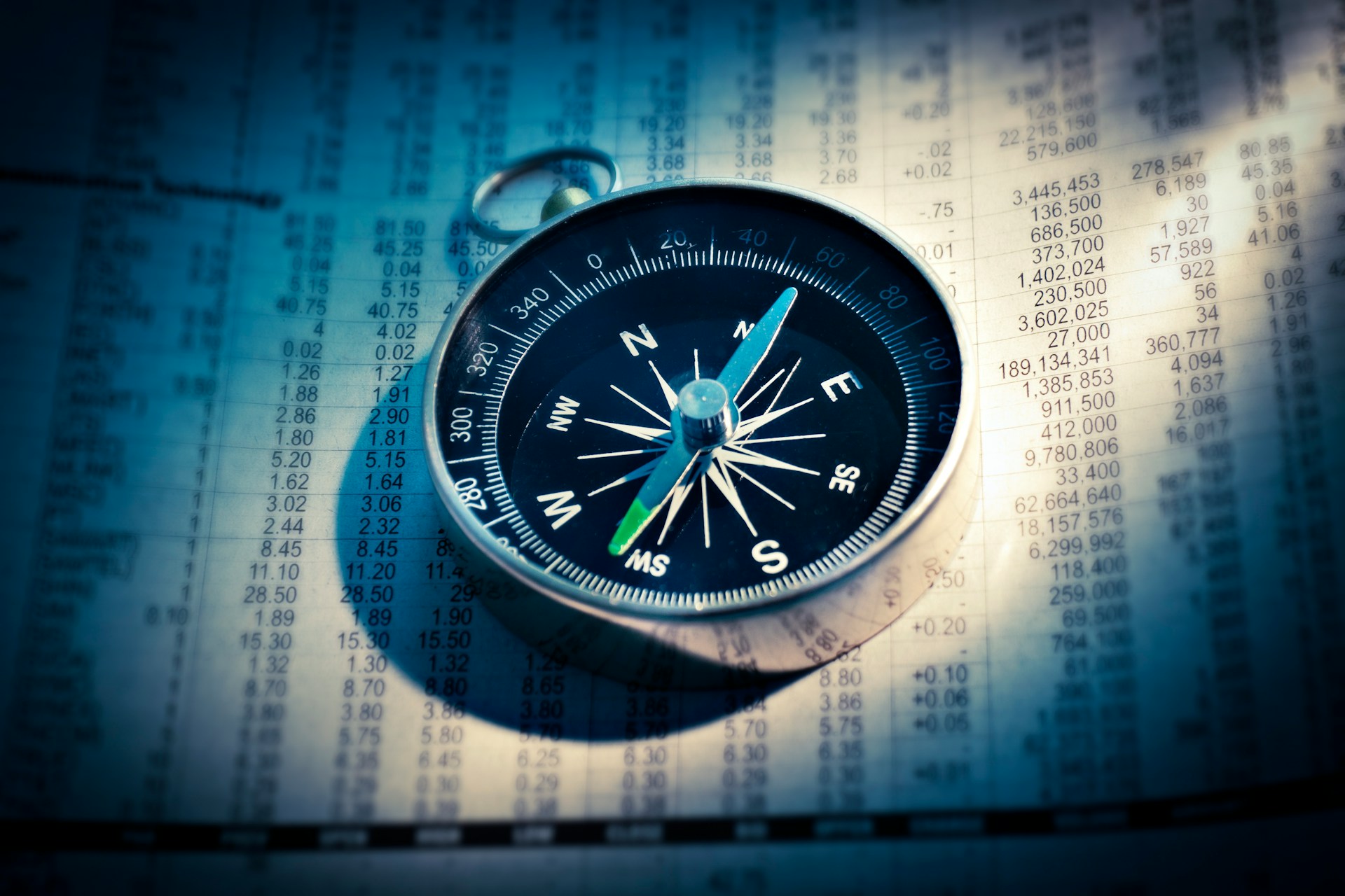 A compass rests on a financial newspaper brimming with numbers and data, guiding the way to insightful money management decisions.