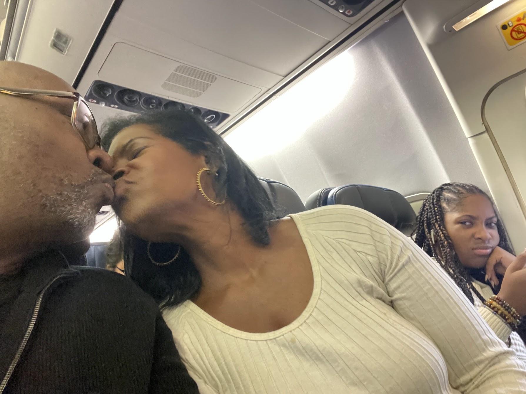 A person and person kissing on a planeDescription automatically generated
