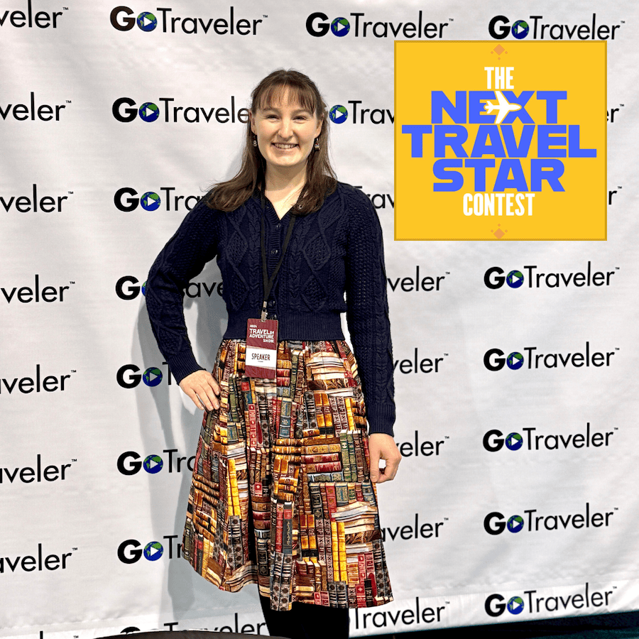 Me wearing my Speaker badge and standing in front of backdrop with GoTraveler logo all over it.
