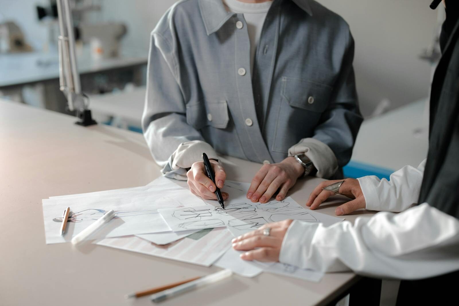 Two fashion designers collaborating on sketches at a bright workspace.
