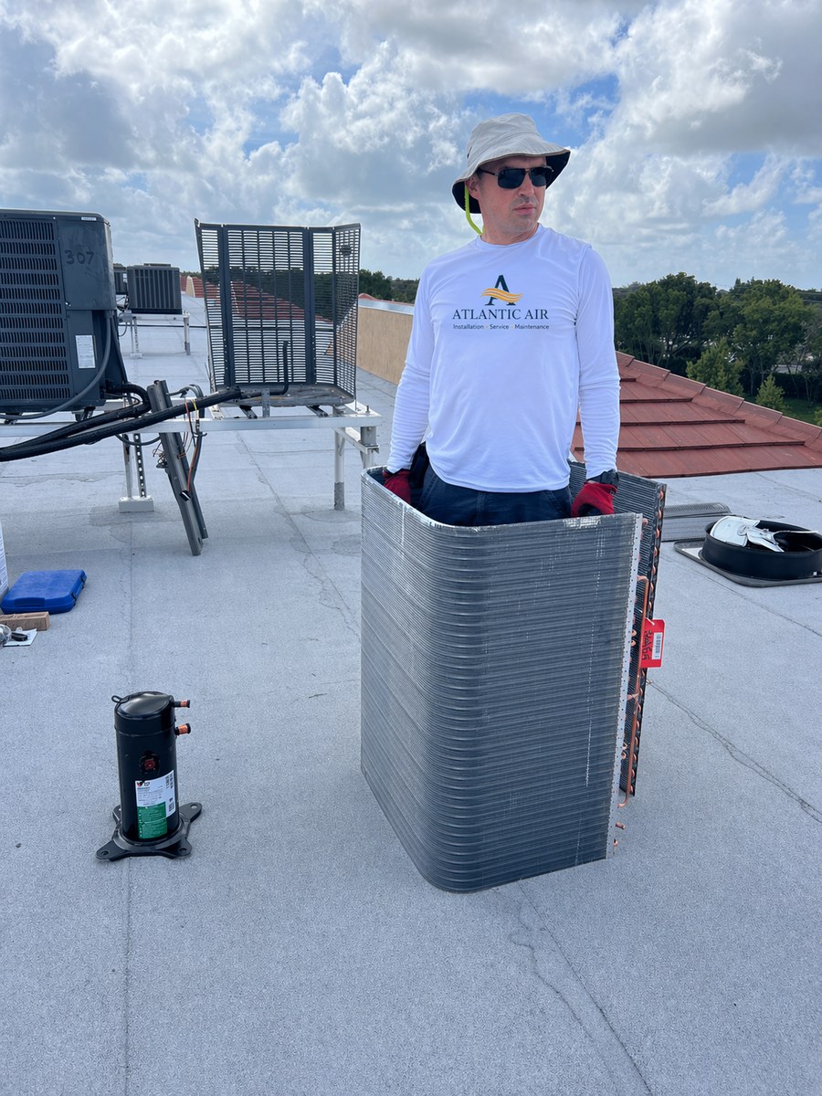 AtlantFlow AC & HEAT technician installing AC coils on rooftop