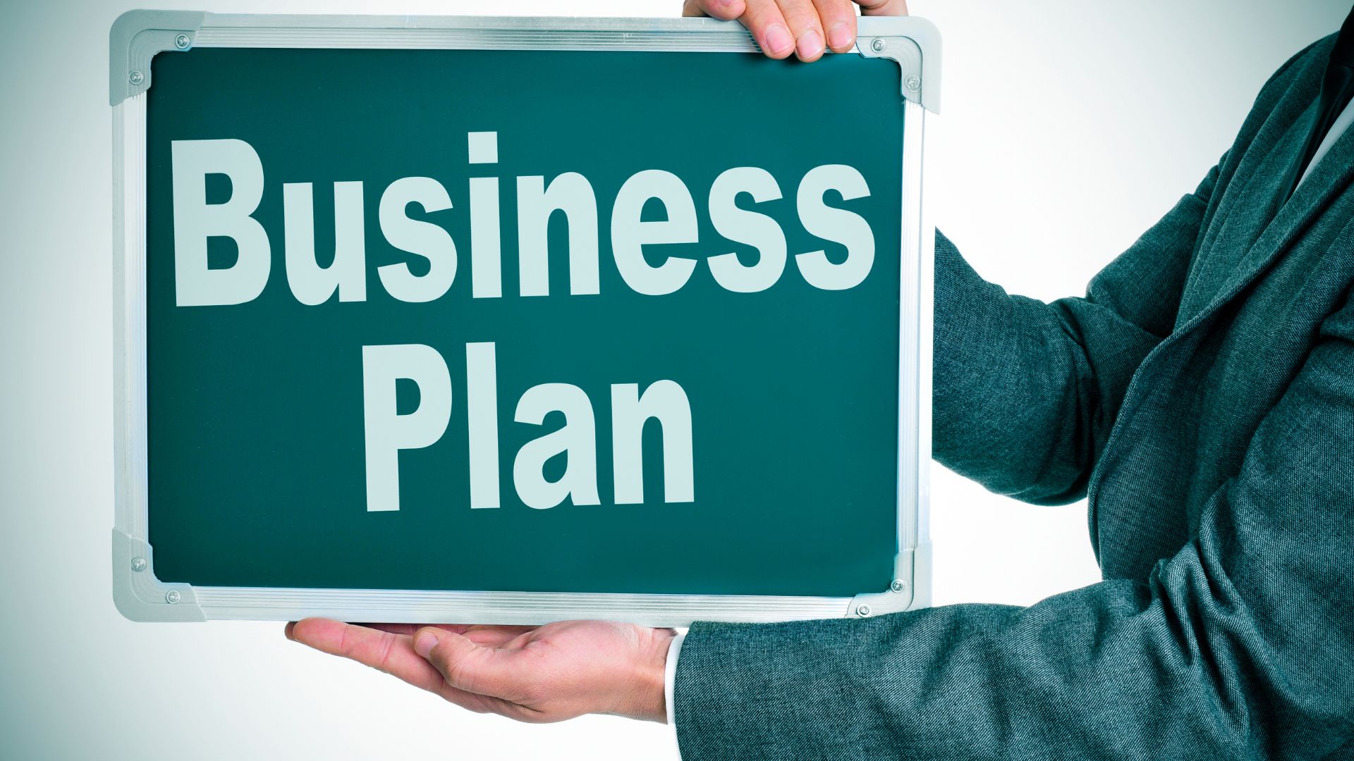 Close-up of hands holding a green sign with the words 'Business Plan' written on it, symbolizing the importance of having a business plan for your startup.