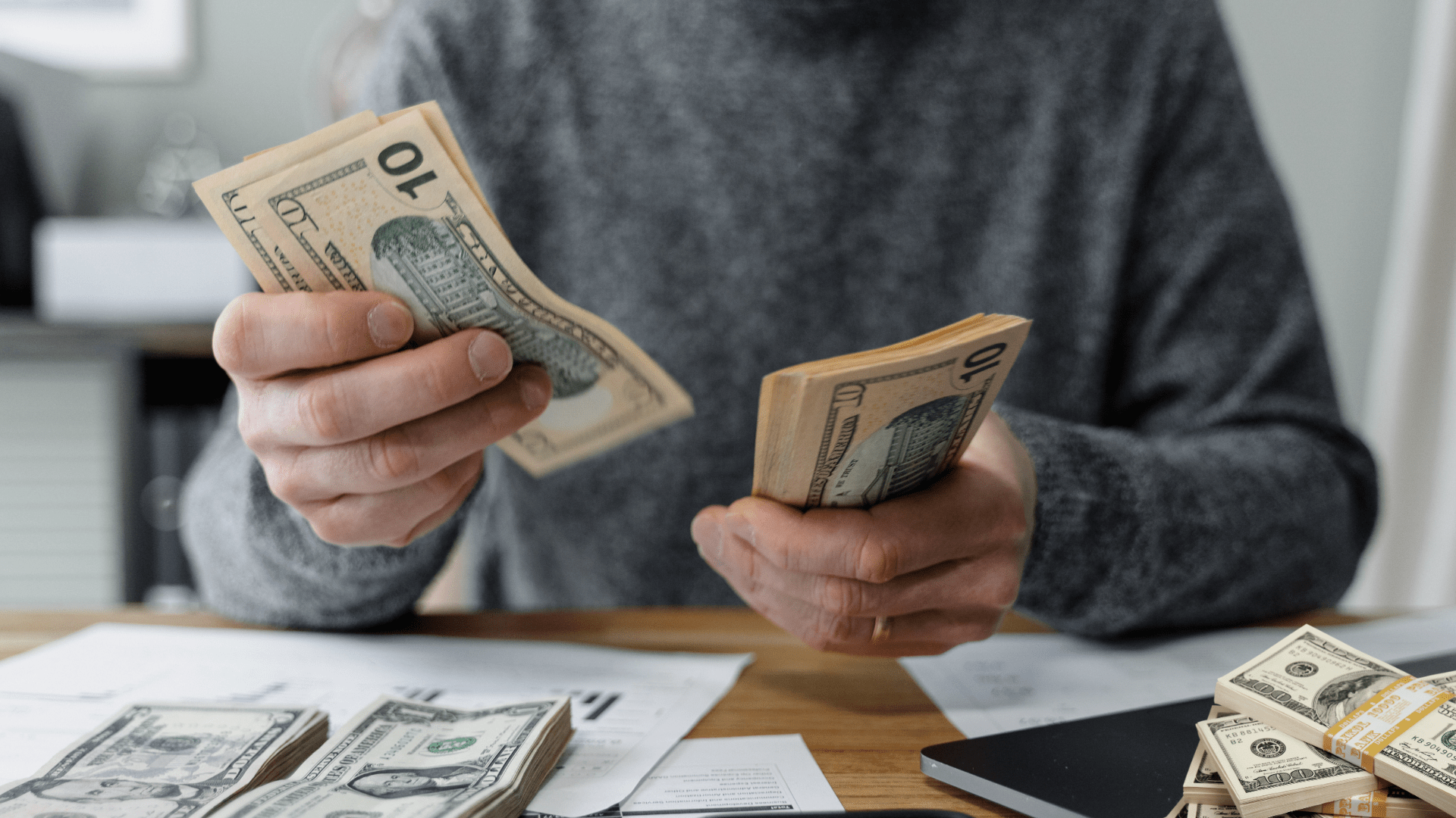 Person counting money, symbolizing small business marketing costs and budgeting.