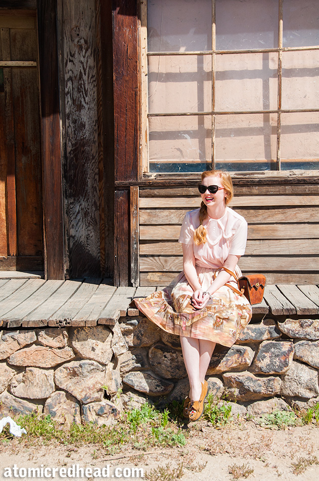 Sitting on the boards and faux rock wall in my outfit I themed for the day, a vintage pale pink nylon blouse, with a vintage border print skirt featuring an illustration of a western town.