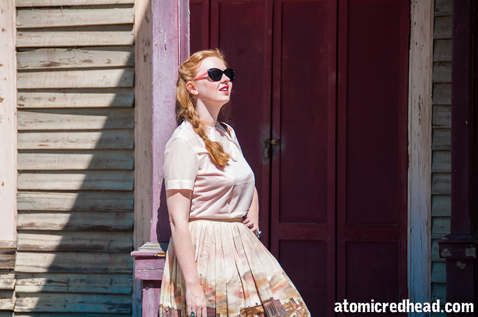 Standing in my outfit I themed for the day, a vintage pale pink nylon blouse, with a vintage border print skirt featuring an illustration of a western town.