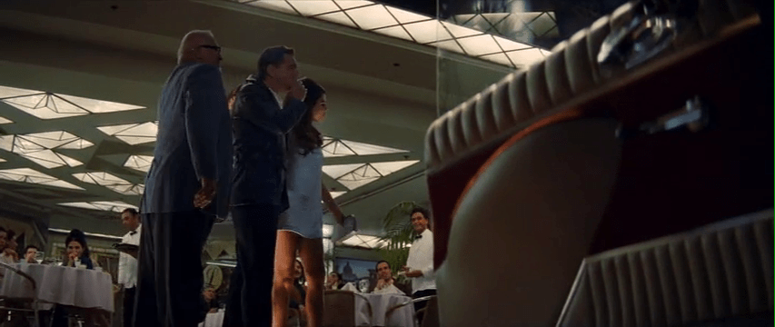 Leonardo DiCaprio and his costar stand in front of an art deco style restaurant.