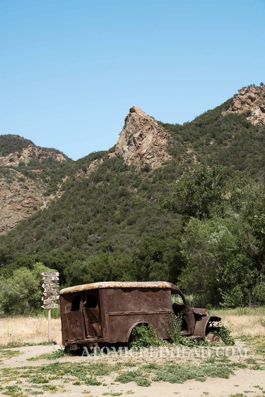 The rusted ambulance sitting in front of the sign post with a high peek in the background, a peek noticeable and seen in the show.