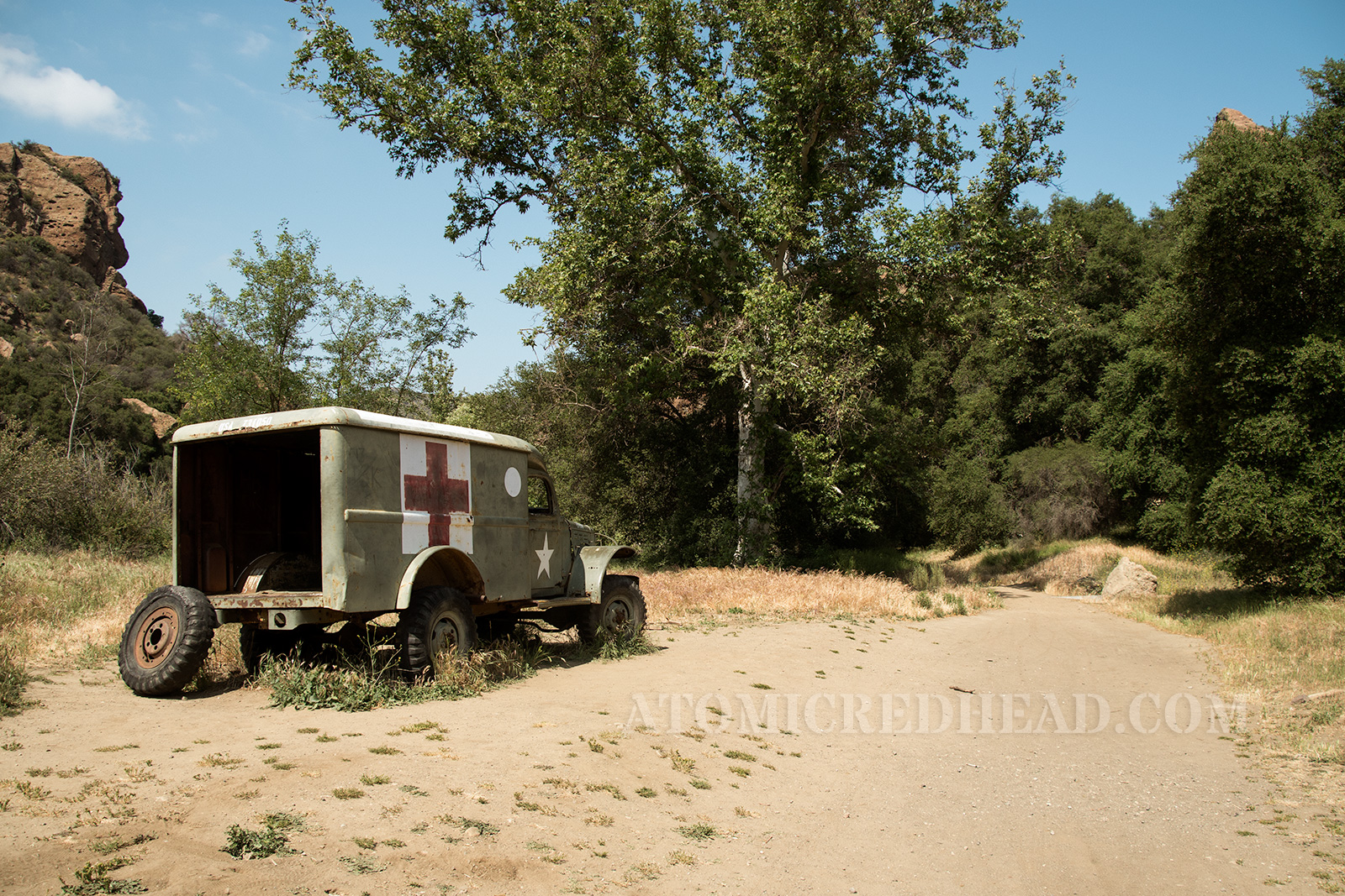A green ambulance with red and white cross on the side, and large white star on the door.