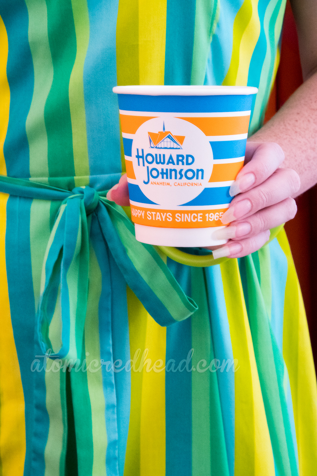 One of the retro HoJo cups, orange and turquoise stripes and a circular logo reading "Howard Johnson Anaheim, Happy Since 1965"