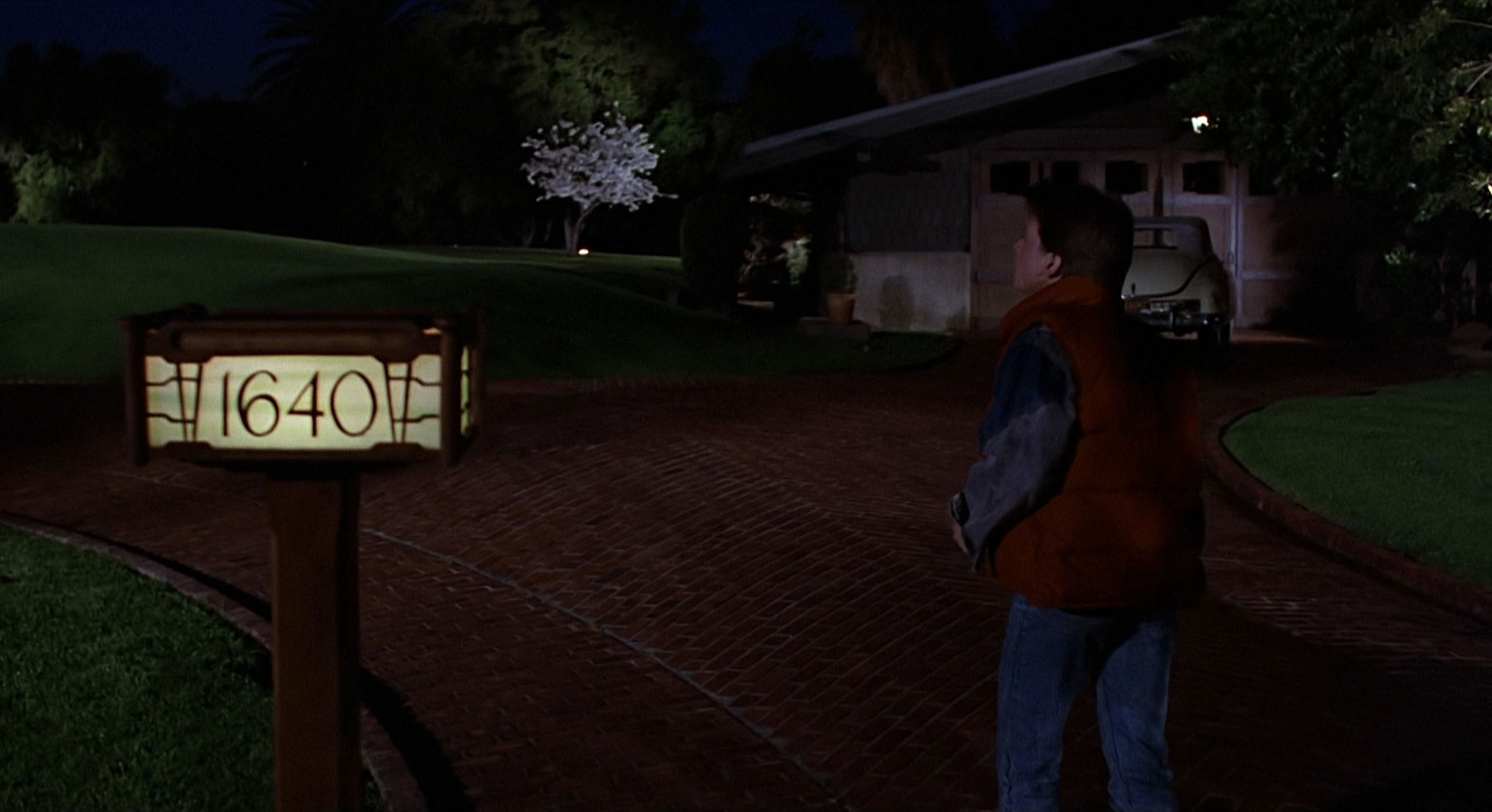 Screencap from Back to the Future - Marty arrives at Doc Brown's House, the garage in the background, the house on the left.