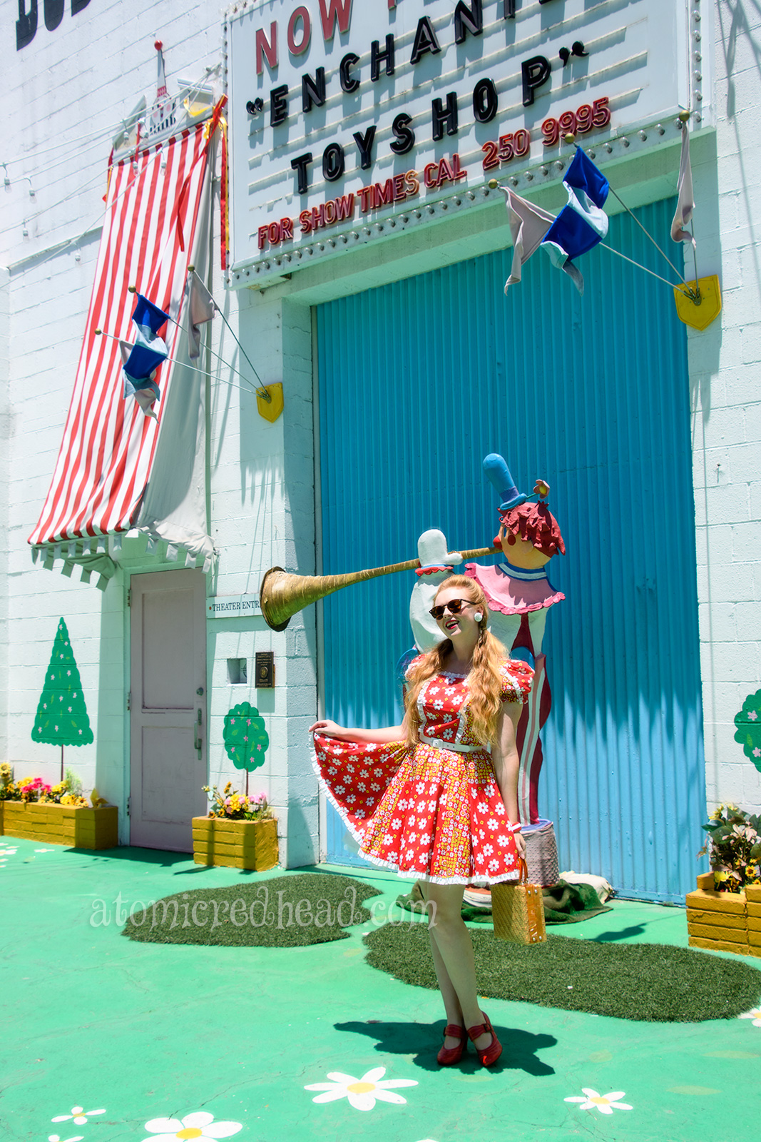 Standing outside of the Bob Baker Marionette Theater. Wearing a red square dancing dress with yellow and white flowers.