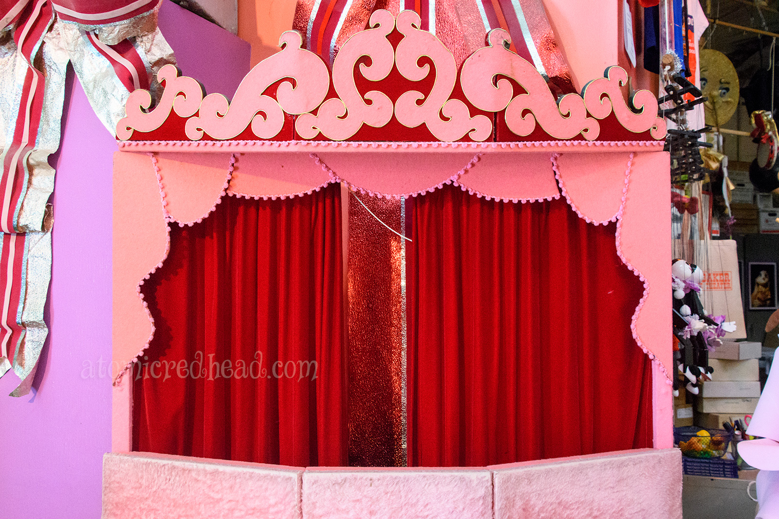 One of the traveling theaters, pink felt swirls around a red curtain.