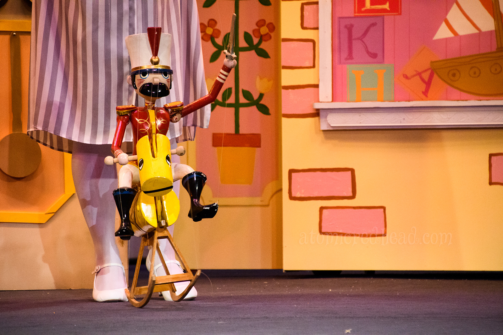 A wooden soldier marionette rides a rocking horse.