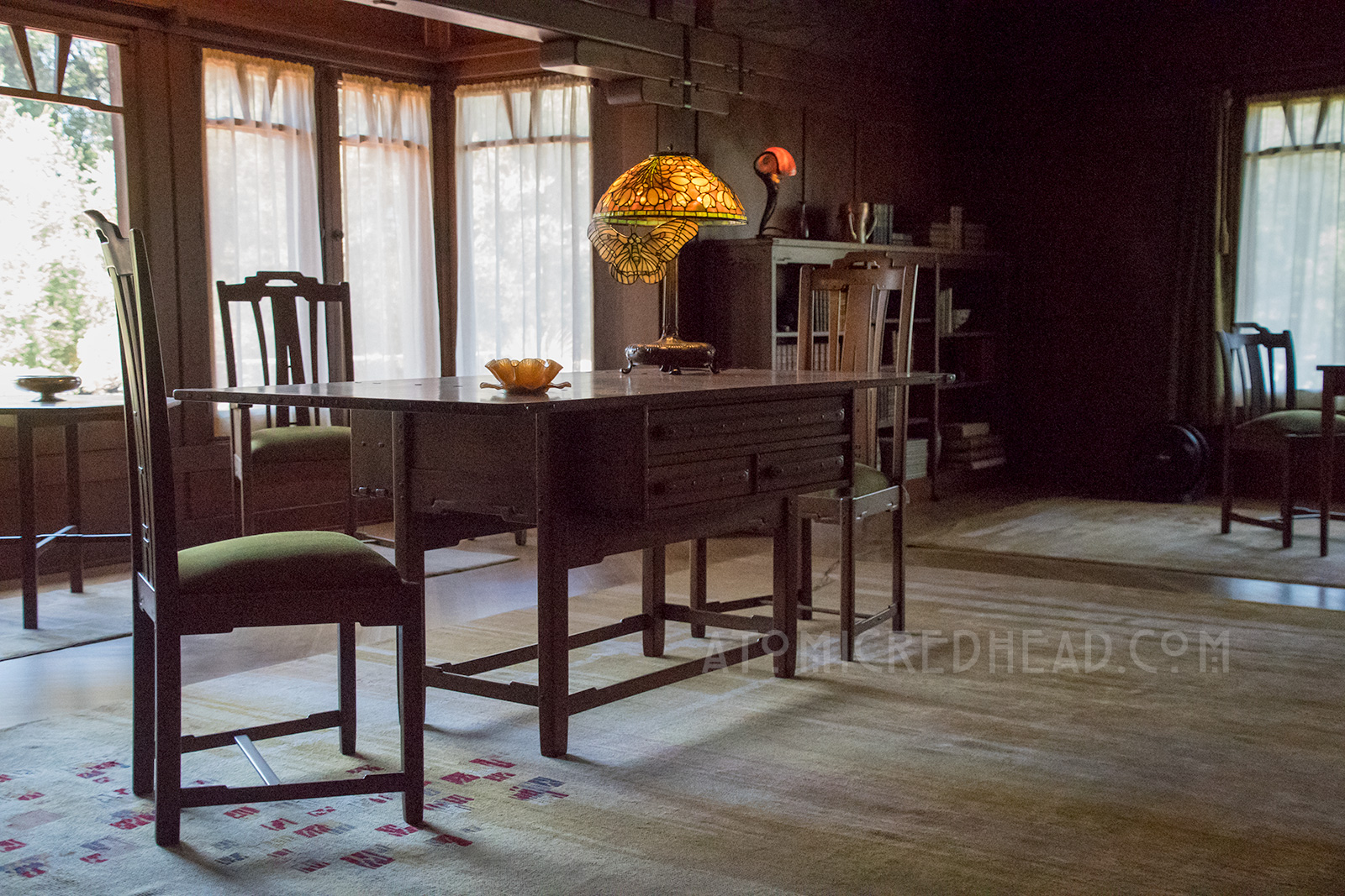 The desk in the living room, with a Tiffany lamp featuring a month.