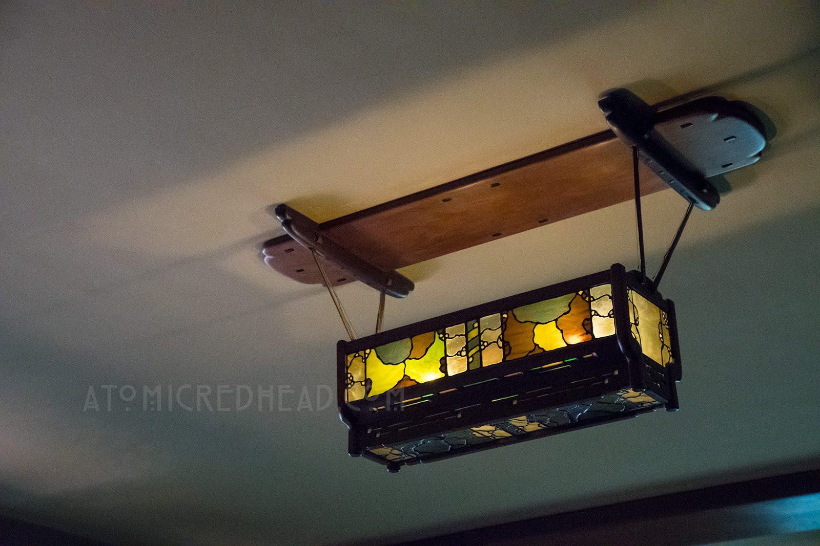 An indirect light fixture of stained glass hangs from the ceiling of the family room.
