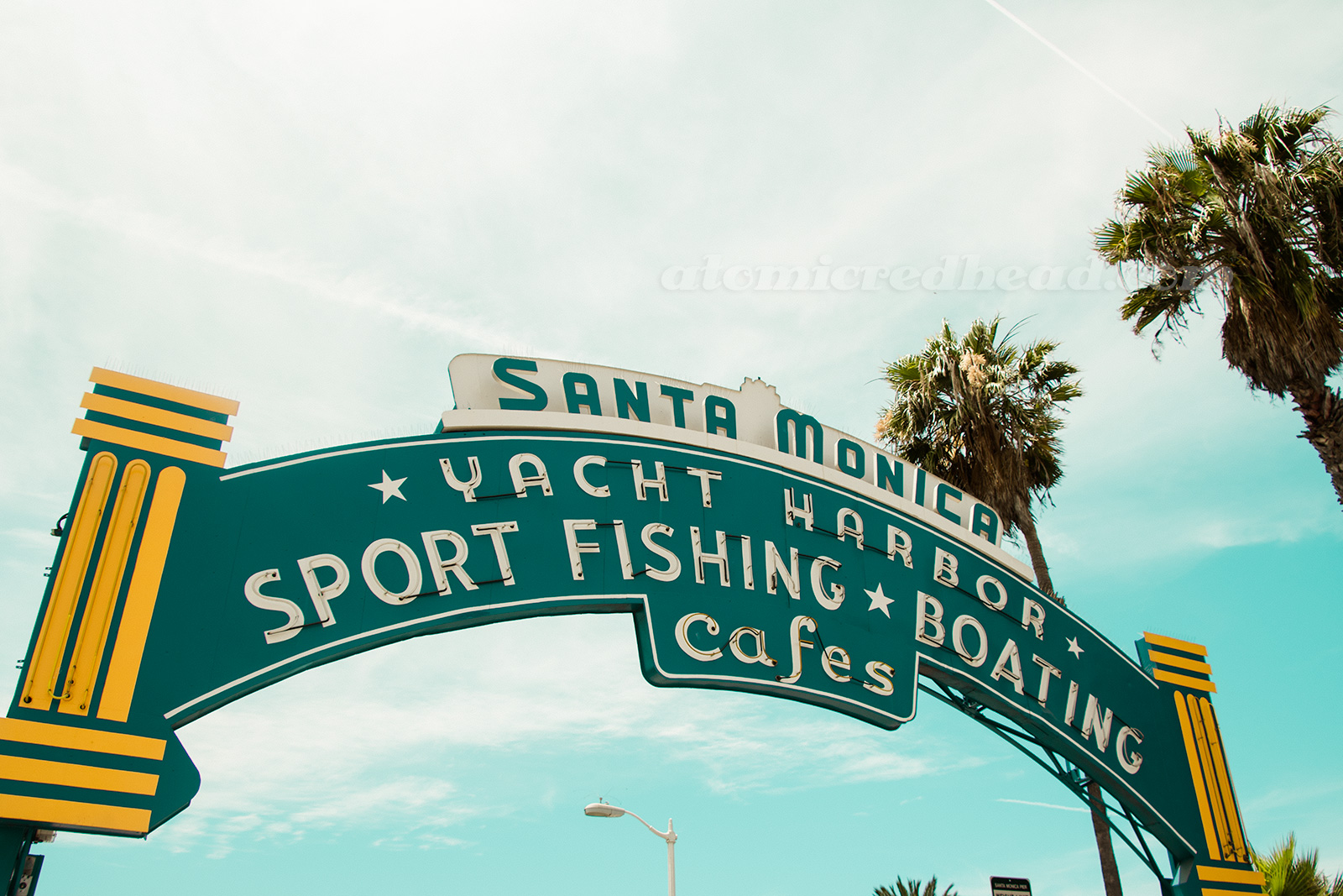 Neon arch above the pier, reading "Santa Monica Yachy Harbor, Sport Fishing, Boating, Cafes"