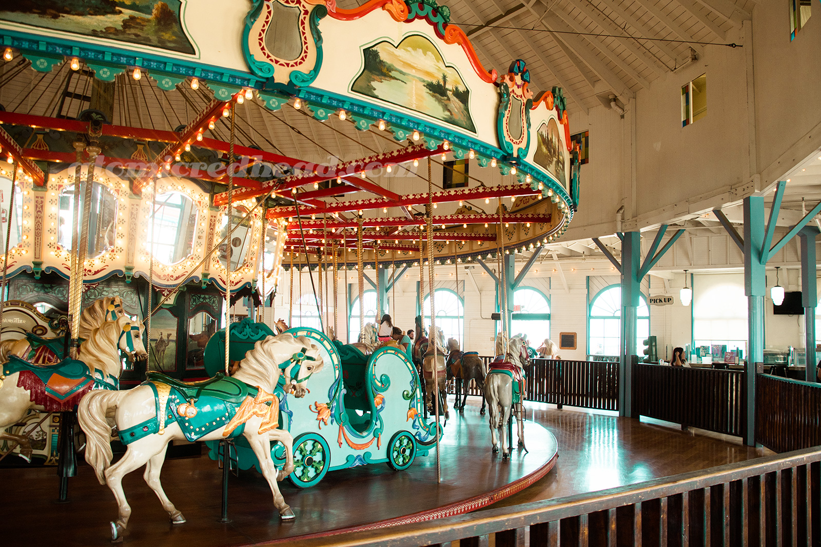 The carousel inside the Hippodrome, horses of a variety of colors, a sleigh painted turquoise also sits upon the carousel.