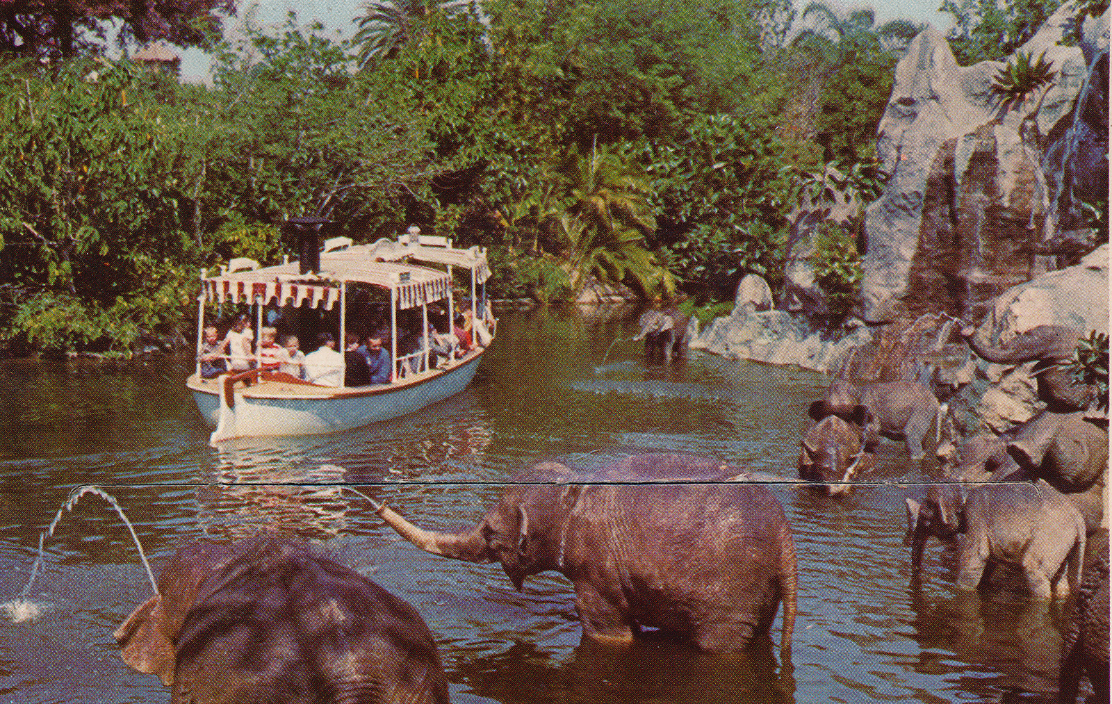 A Jungle Cruise boat glides through the sacred elephant bathing pool with a variety of elephants.