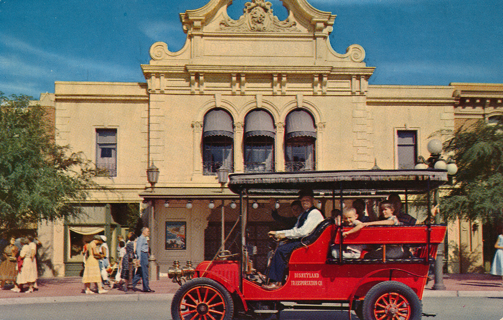 A red horseless carriage in front of the Opera House.