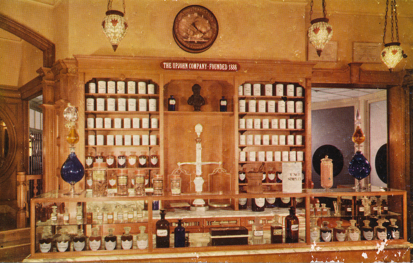 Inside the pharmacy, warm with light colored wood and cold bottles along the back. 