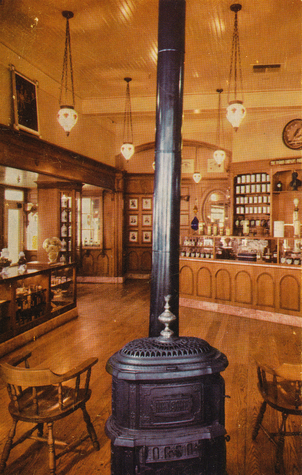 Inside the pharmacy, with a potbelly stove and warm wood walls and old bottles lining the walls.