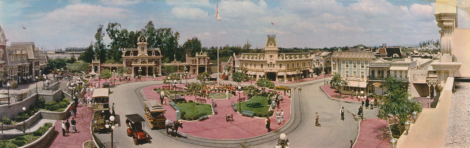 Large panoramic of Disneyland's Main Street, sweeping from the train station on the left, followed by City Hall, then the Emporium, and the Wurlitzer shop on the left.