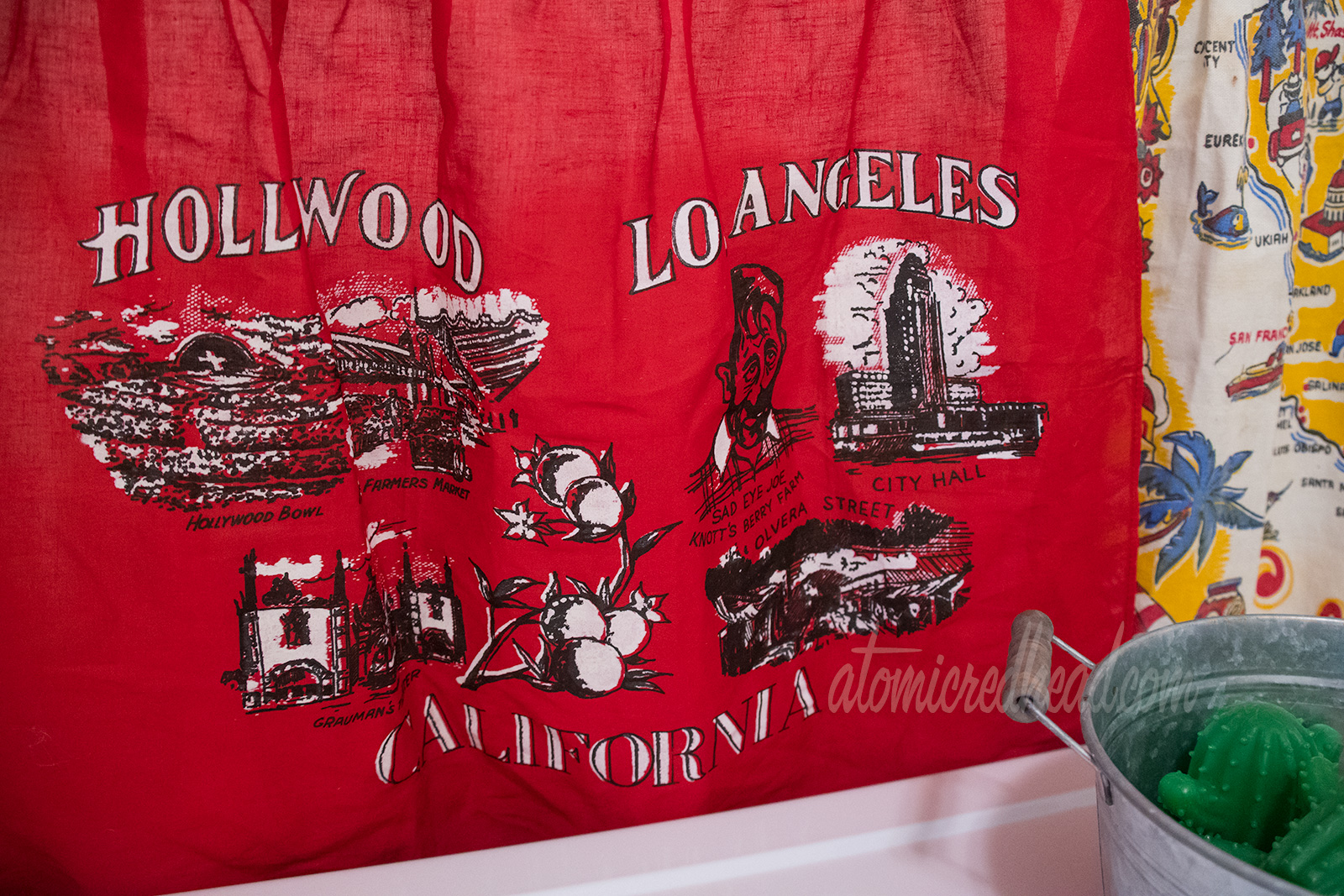 Close-up of the red apron. Across the top it reads "Hollywood Los Angeles" and across the bottom "California." The illustrations include the Hollywood Bowl, Farmer's Market, Grauman's Theater, Sad Eye Joe of Knott's Berry Farm, Los Angeles City Hall, and Olvera Street.