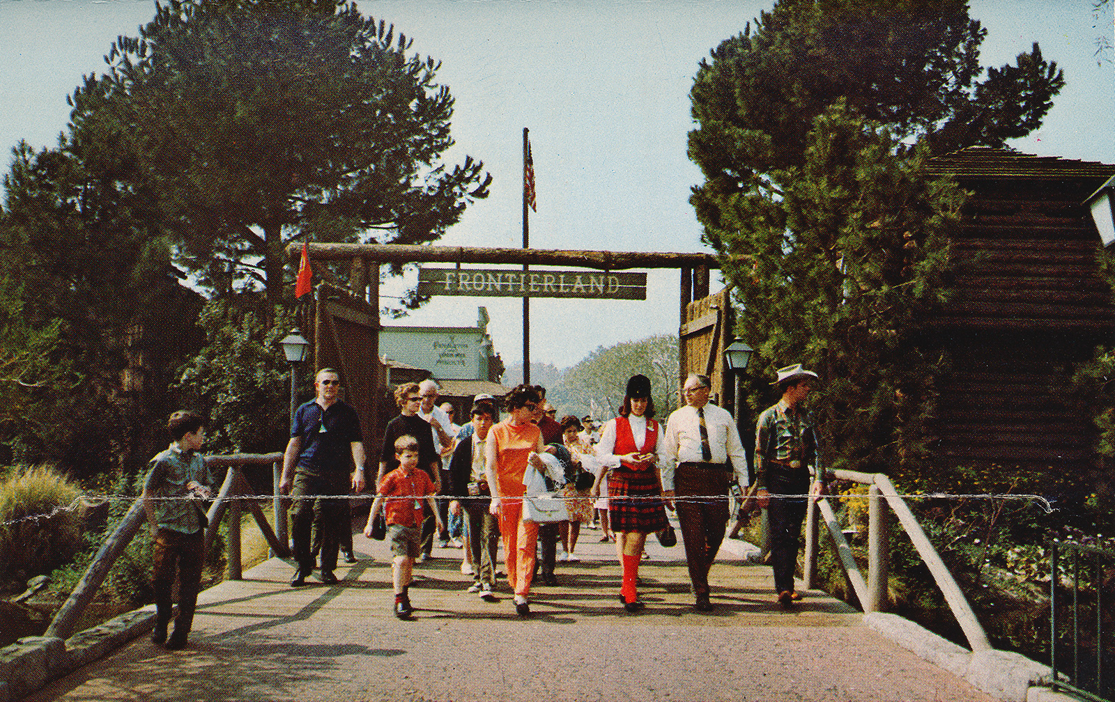 The entrance to Frontierland, which looks like an old fort, made of logs, a large sign reading "Frontierland" hangs over the gateway.