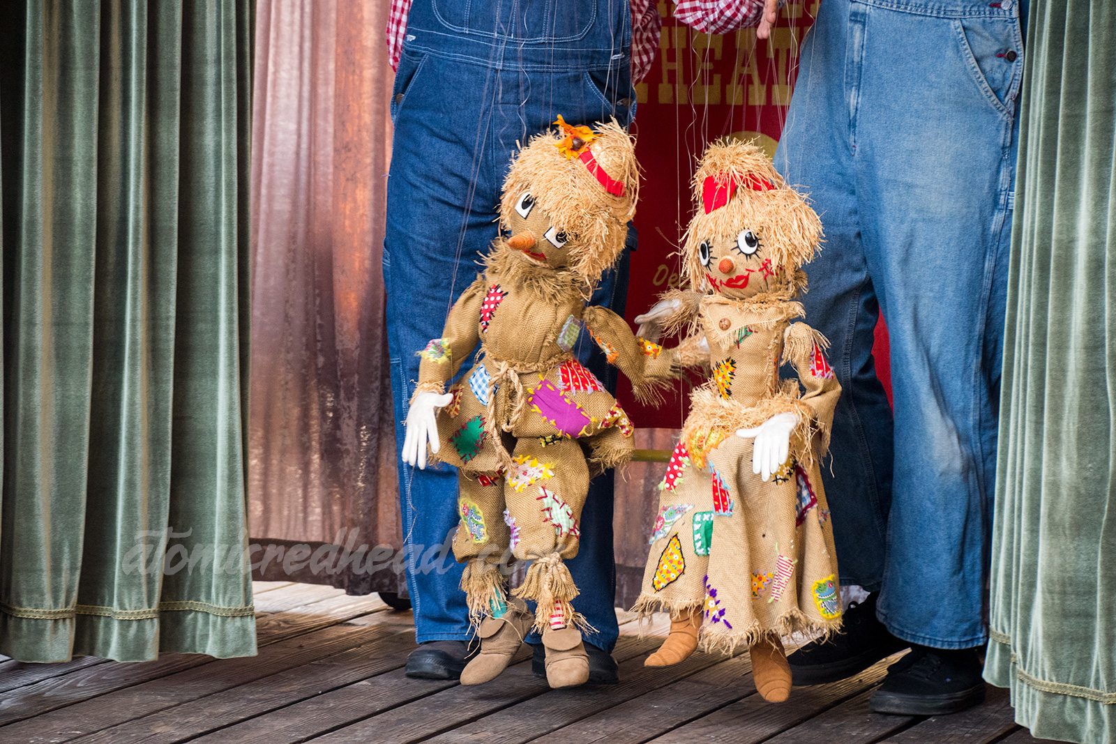 A pair of scarecrow marionettes made of burlap with patches. 