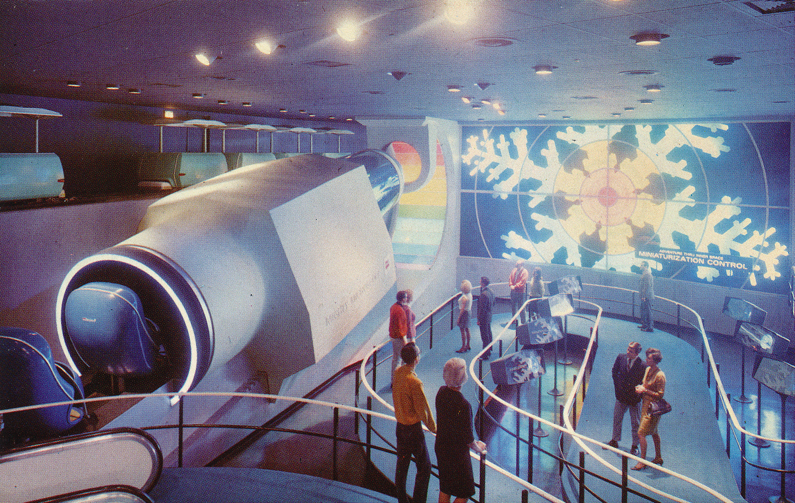 A large "shrinking" machine stands on the left, as guests walk through the area on the right. A large screen of a snowflake on the back wall.