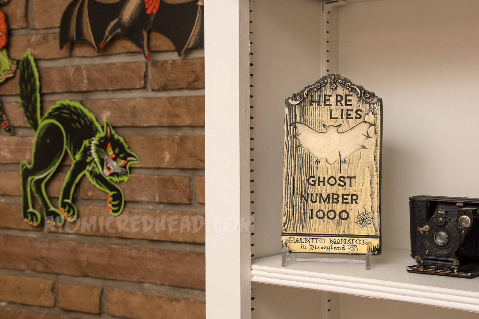 A small tombstone reading "Here Lies Ghost Number 1000 Disneyland's Haunted Mansion"