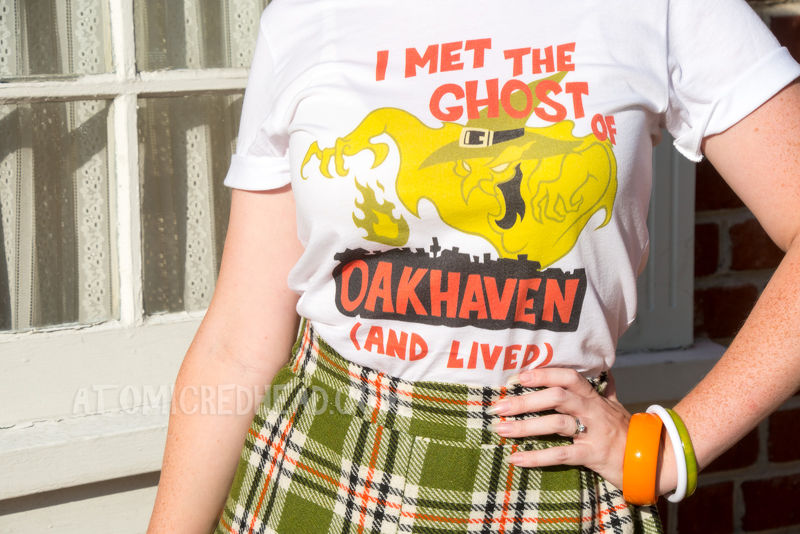 Close-up of my shirt - a frightening green ghost of a witch rises from the silhouette of a town. Above reads "I MET THE GHOST OF" and within the town's silhouette reads "OAKHAVEN" and below "(AND LIVED)"