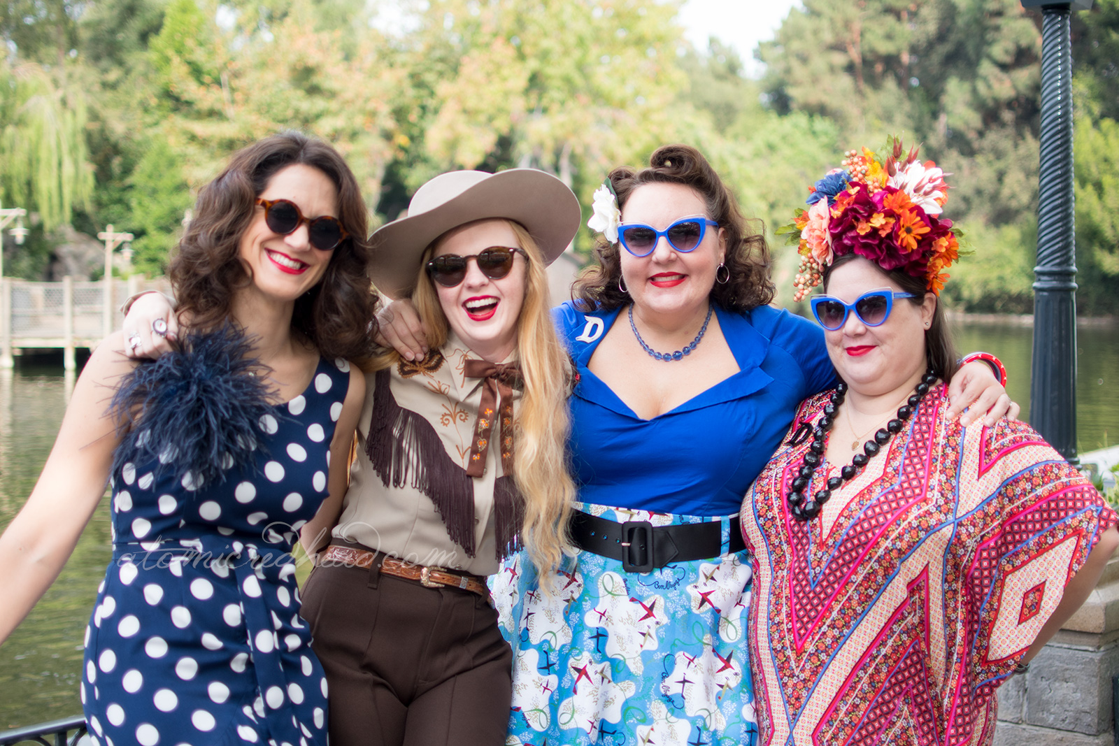 From left to right, my friend Nikki, wearing a navy dress with large white polka dots, myself, my friend Dor, wearing a bright blue top with a skirt of blue and white with airplanes, and my friend Kaitlyn, wearing a red, white, and navy blue patterned dress and a large floral crown.