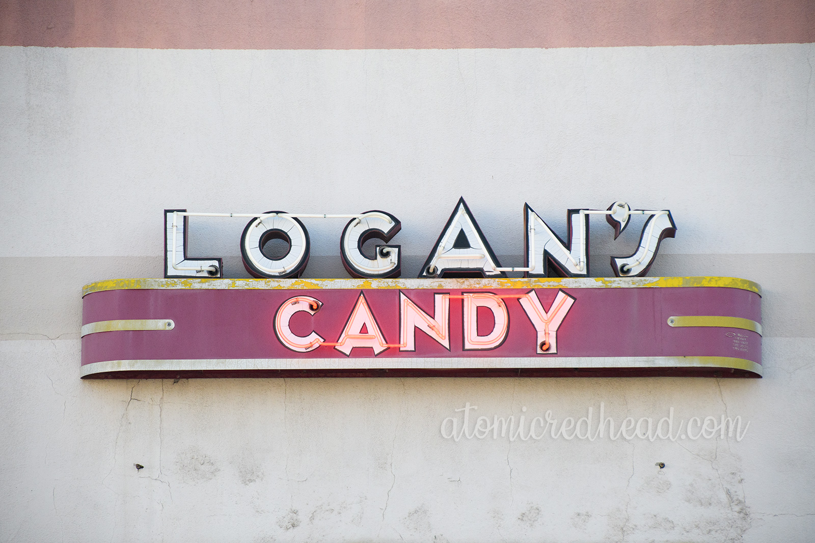 Logan's Candies spelled out in flickering white and red neon.