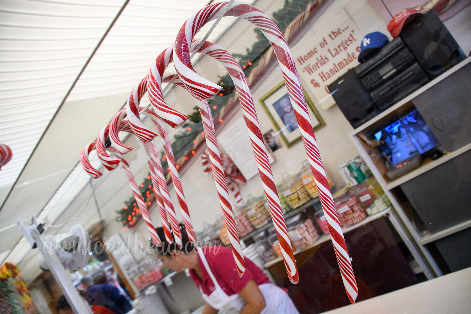 Red and white candy canes of various sizes hang on the window wall between the shop and the candy making space.