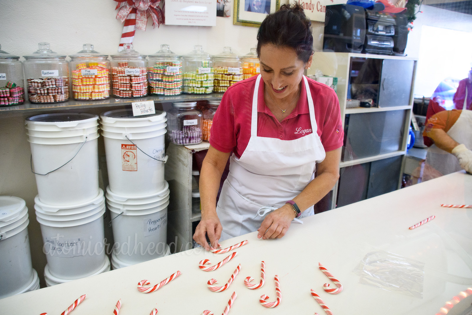 A candy maker hand bends the crook of the candy cane.