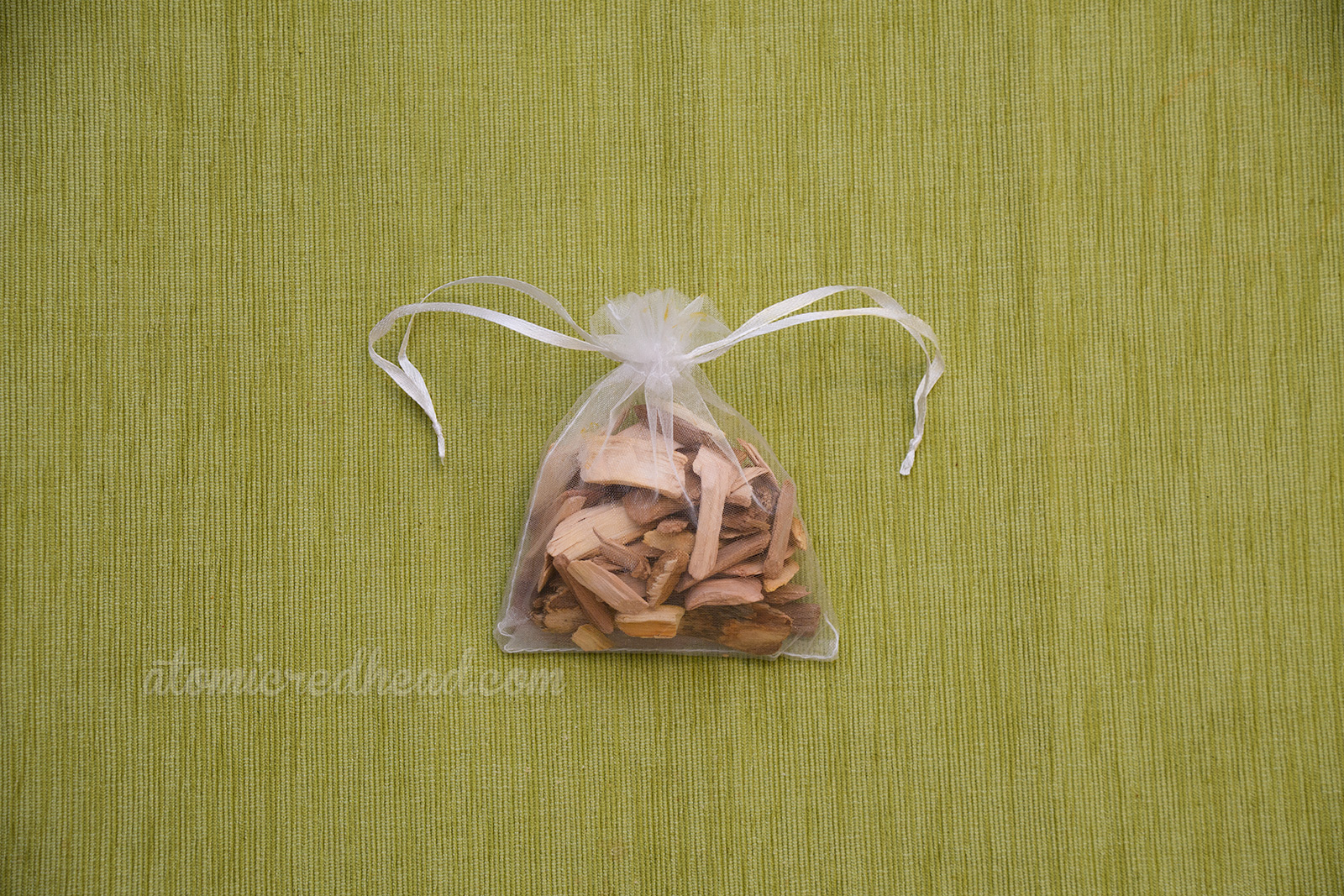 A small organza sachet bag is filled with wood chips.