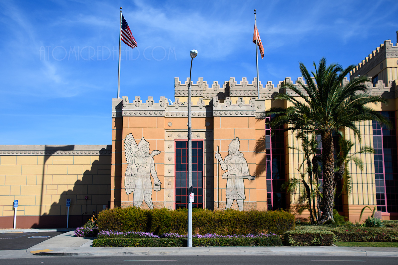 On either side of a window of the "palace" are two figures. One is a winged man, known as a genie, the other is a man holding a staff and resembles the real Assyrian king, Lomg Sargon.