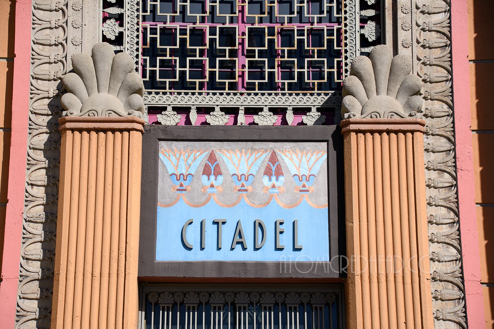 Close-up of the sign above the main doors, a blue sign reading "CitadeL" with tan and maroon lotus flowers.