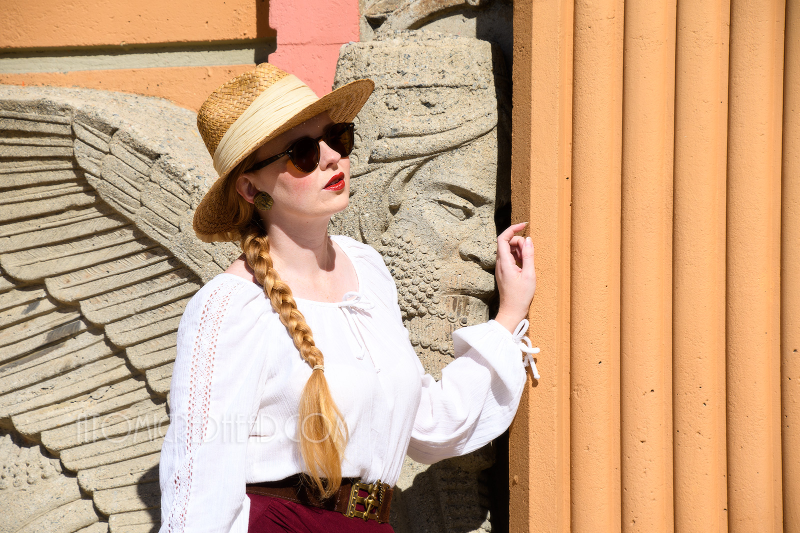 Myself standing outside the main doors, wearing a straw hat, a white peasant top, and maroon skirt that features gathering in an asymmetrical design.