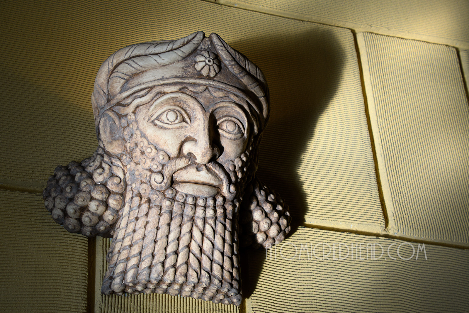 Assyrian male faces are wall sconces, they have long twisted bears and long curly hair and small short crowns. 