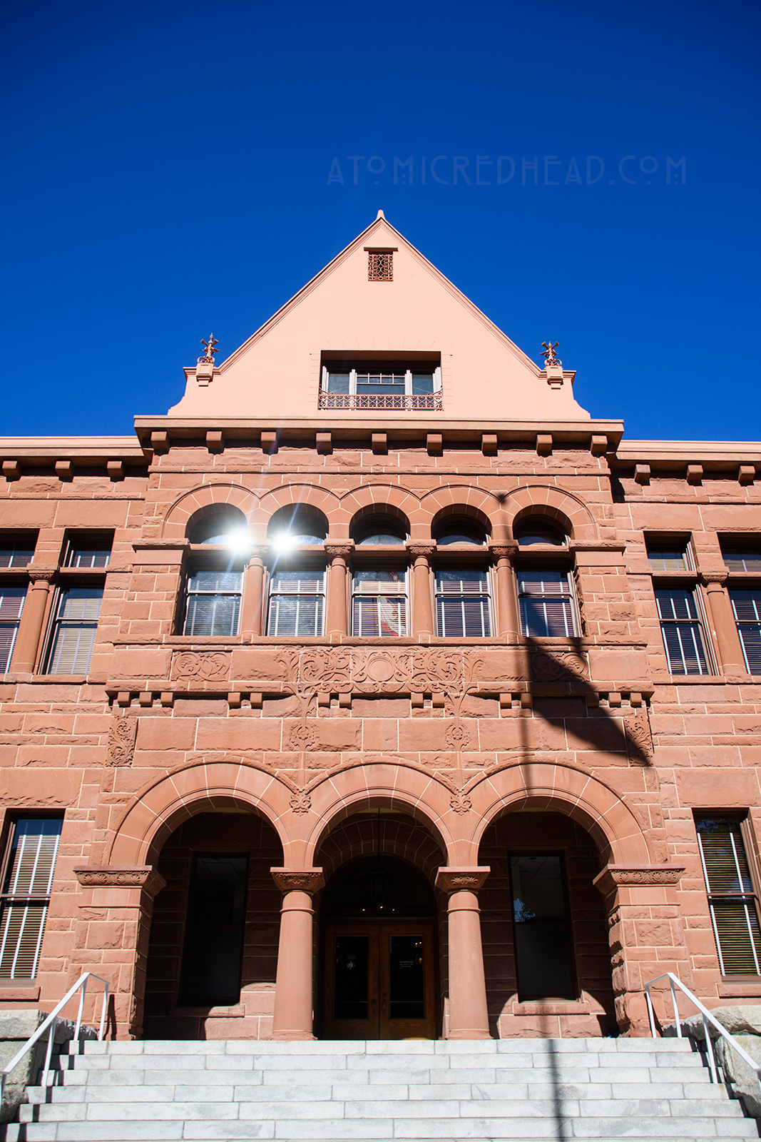 The Old Orange County Courthouse, a large, three-story building made of red sandstone. It features three small arches in the center mark the entrance. Three gables top the roofline.
