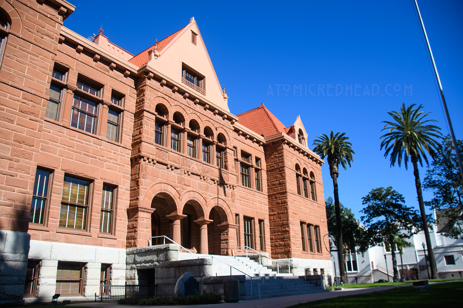 The Old Orange County Courthouse, a large, three-story building made of red sandstone. It features three small arches in the center mark the entrance. Three gables top the roofline.