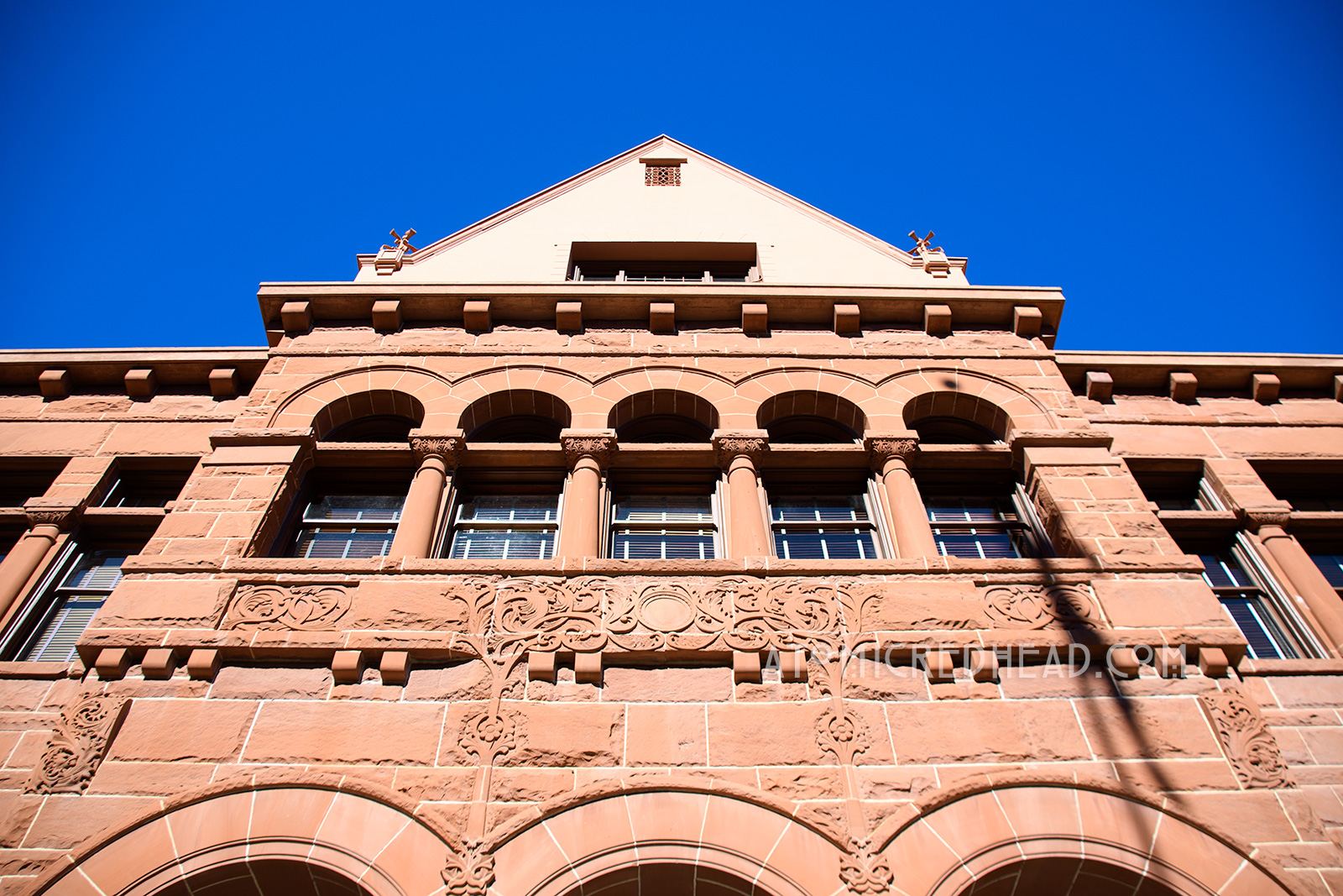 The Old Orange County Courthouse, a large, three-story building made of red sandstone. It features three small arches in the center mark the entrance. Three gables top the roofline.