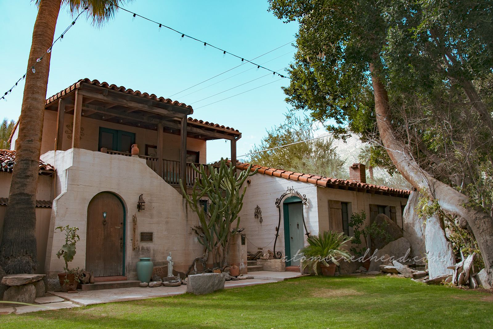 A small Mediterranean style home with two large palm trees.