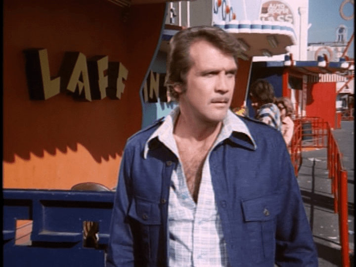 Screencap: Steve Austin looks into the distance in front of the Laff in the Dark building.