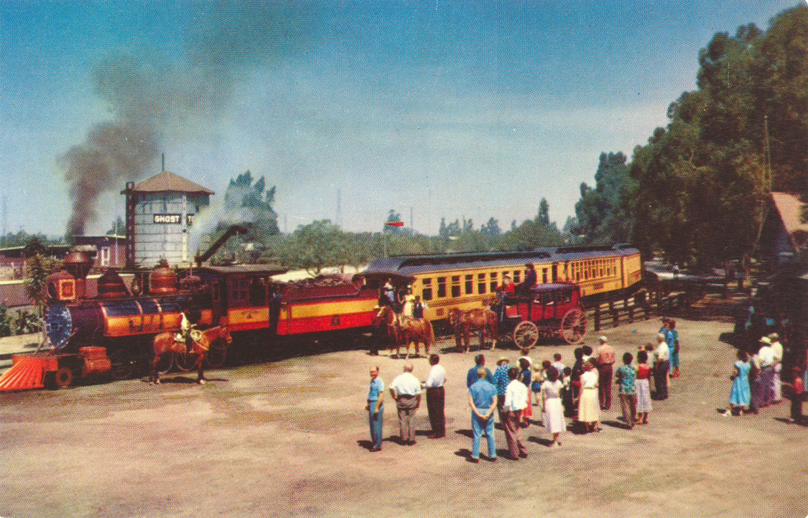 The Ghost Town train chugs past guests standing nearby.